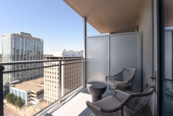 A balcony with two chairs and a table overlooks a cityscape at Two Twelve Clayton Apartments, Clayton
